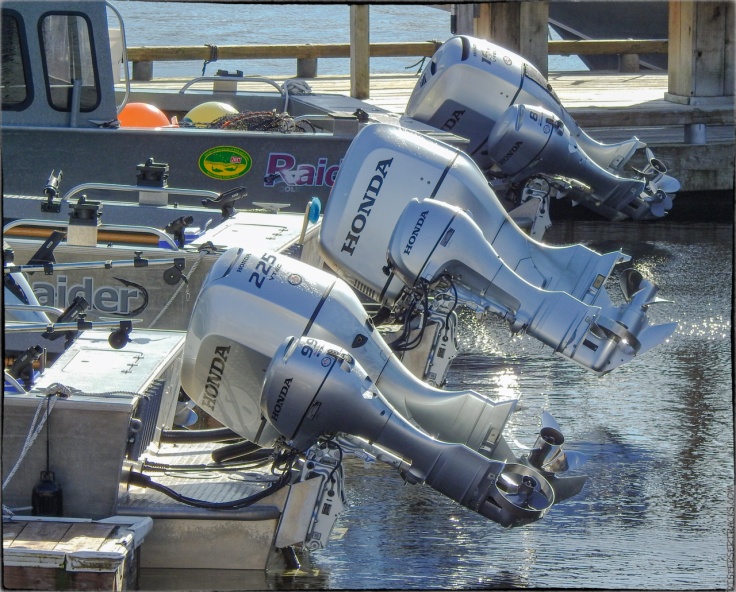 three boats with their outboard motors lifted out of the water