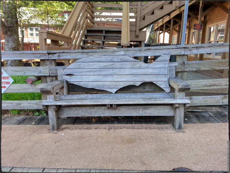 A woodden bench with the shape of a salmon for the back support